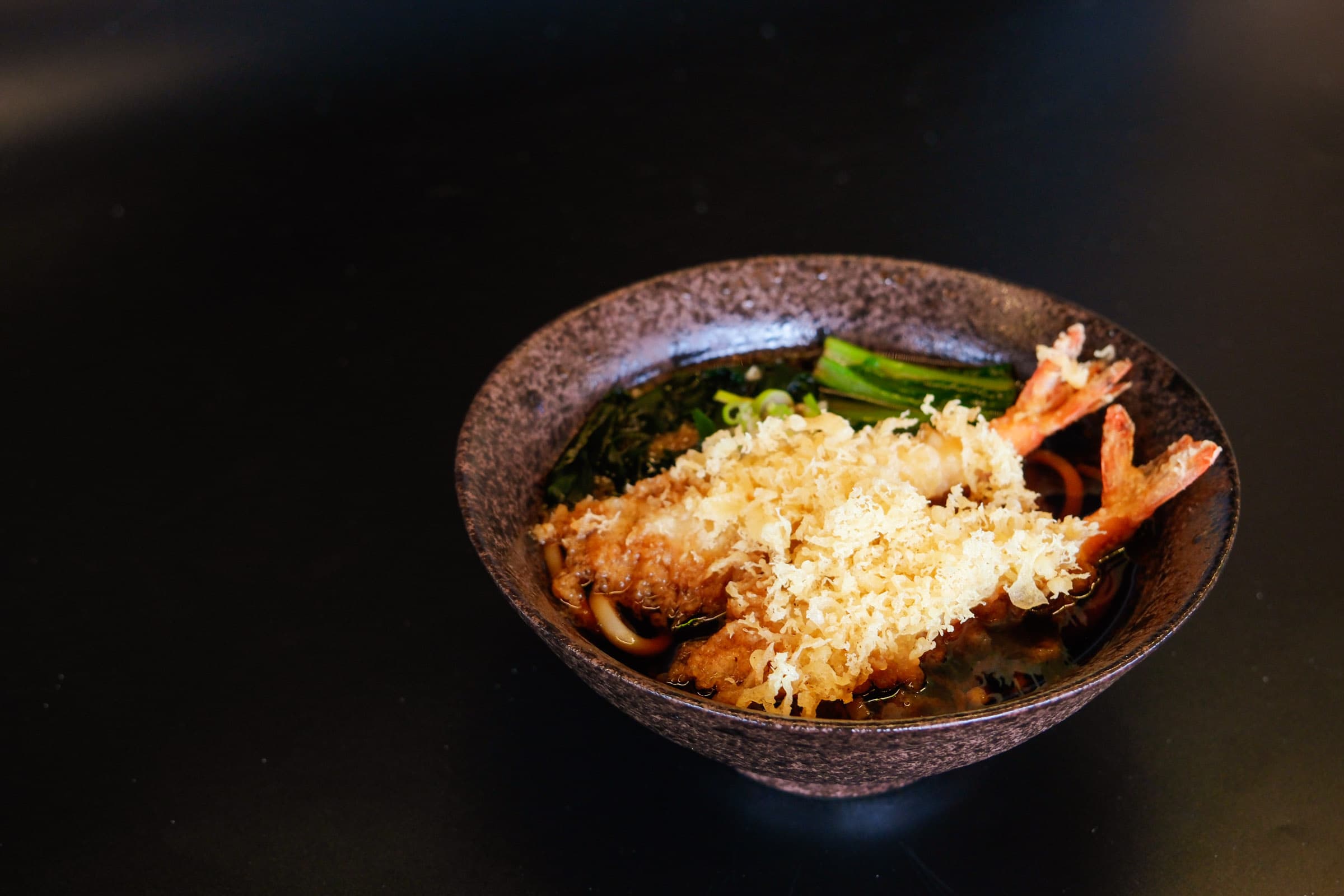 Crispy tempura prawns served over warm udon noodles